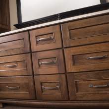 A large, dark-finished wooden dresser with metal handles and a mirror hung above it, occupying a significant portion of a room.