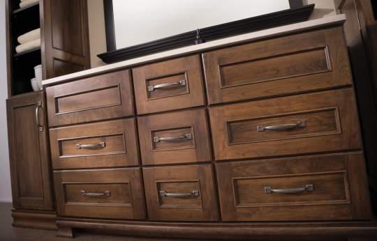 A large, dark-finished wooden dresser with metal handles and a mirror hung above it, occupying a significant portion of a room.